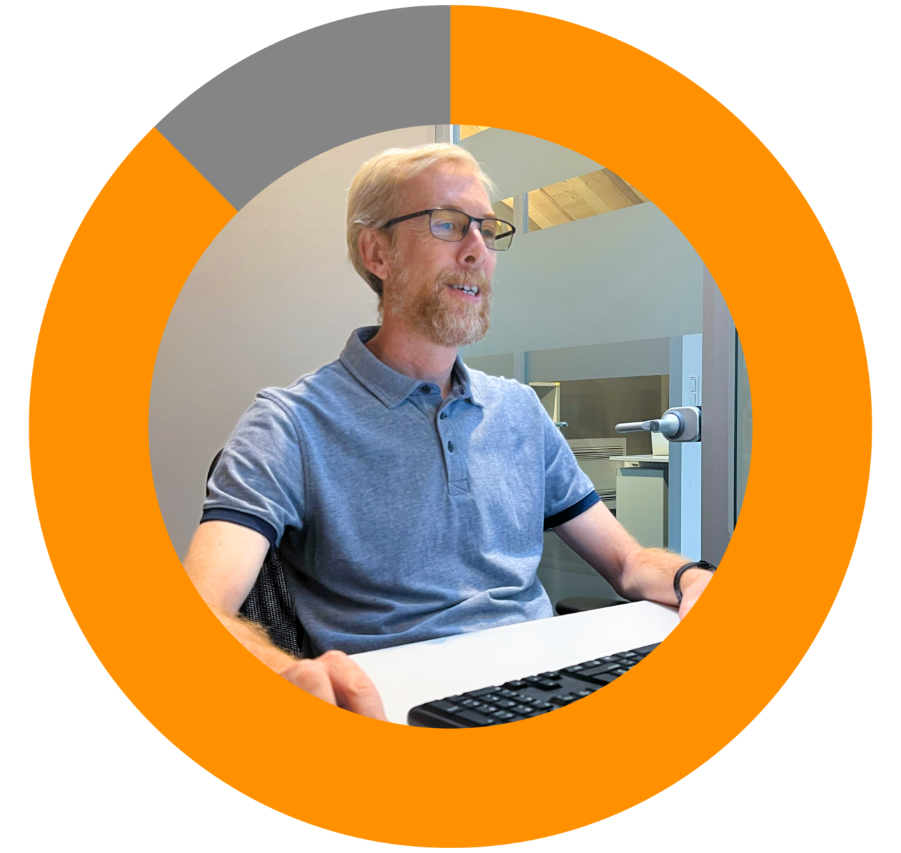 Red-bearded man with glasses smiles while working on a laptop in an office, framed by THRON's circular logo.